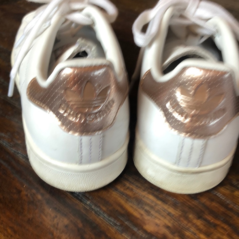 Stan Smith all white tennis shoes with rose gold accent.